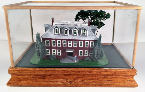 A scratch built maquette of a red house used in the Landscape oil painting 'Red House', inside a glass case, by Phil Fake